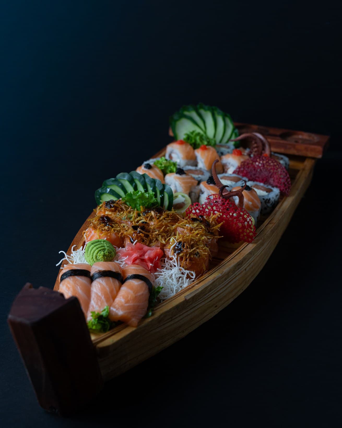 Barco de madera con rolls de sushi sobre fondo negro